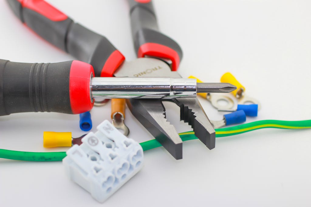 A detailed close-up of hand tools including a screwdriver and pliers with various wiring accessories.